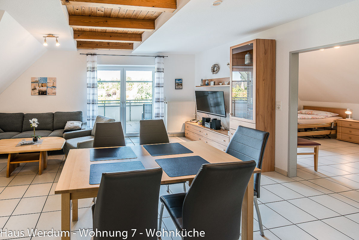 Offene Wohnküche der Wohnung 7 im Haus Werdum mit großem Esstisch, Küchenzeile, Wohnbereich, Balkonzugang und offenem Zugang zu Schlafzimmer 1. Laut „Reisen für Alle“ misst der Wohnraum etwa 6 × 6 m; der schmalste Durchgang beträgt 160 cm.