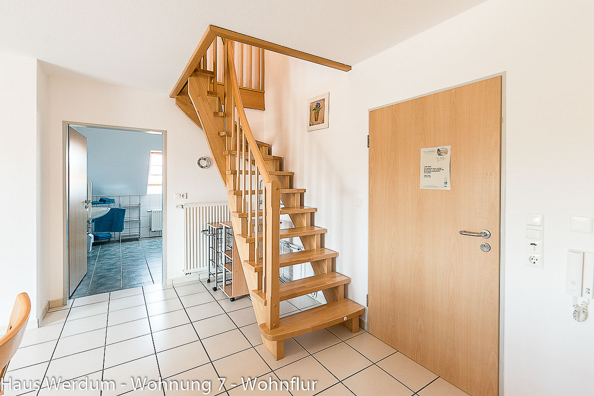 Innenliegende Holztreppe in Wohnung 7 als Zugang zum höher gelegenen Schlafzimmer 2. Der Zugang führt über mehrere Stufen und ist daher nicht barrierefrei und nicht rollstuhlgerecht; der angrenzende Wohnbereich ist separat zu beurteilen.