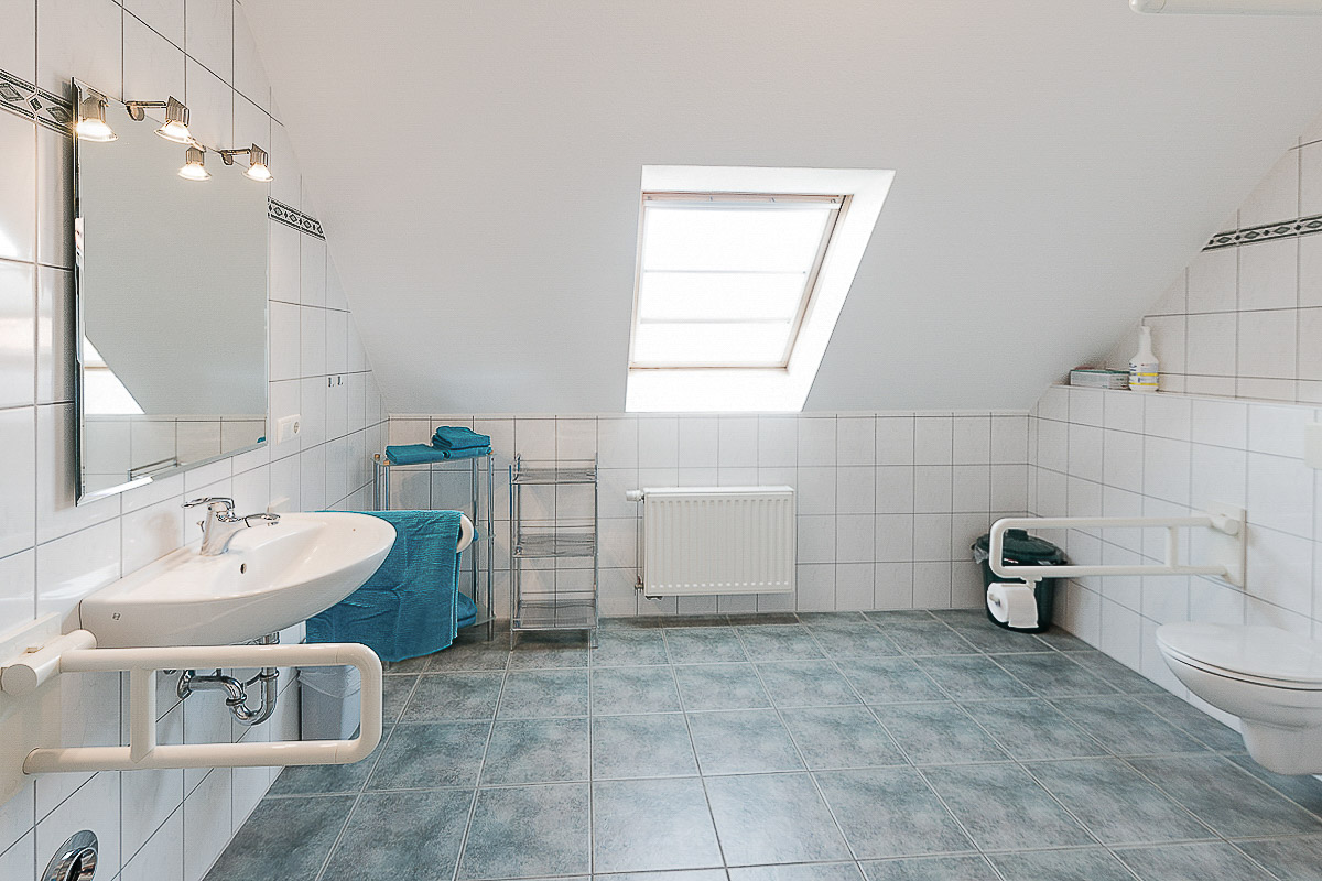 Waschplatz im Bad der Wohnung 7 mit freiem Bereich unter dem Waschbecken und seitlichen Stützgriffen. Laut Reisen für Alle stehen davor 333 × 212 cm Bewegungsfläche zur Verfügung; die Waschbeckenoberkante liegt bei 85 cm.