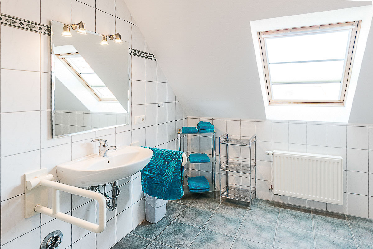 Offenes Waschbecken im Bad der Wohnung 7 mit seitlichen Stützgriffen, Spiegel und freiem Bereich darunter. Geprüfte Bewegungsfläche vor dem Waschbecken: 333 × 212 cm; Waschbeckenoberkante 85 cm.