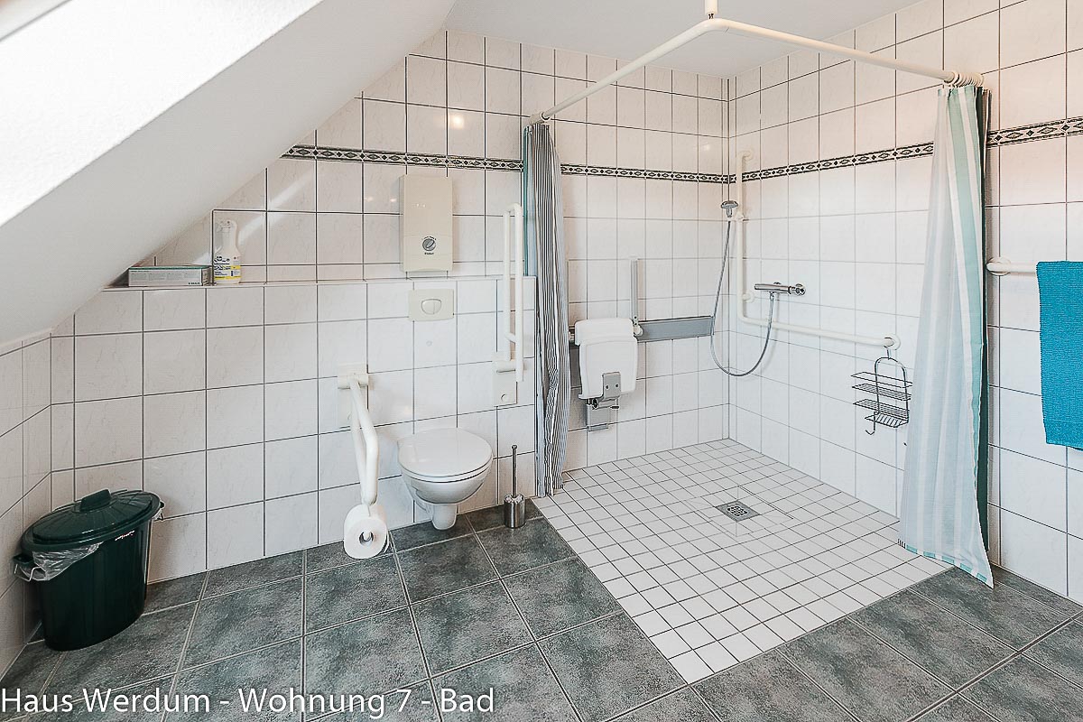 WC mit seitlichen Stützgriffen neben bodengleicher Dusche mit Klappsitz und Haltegriffen in Wohnung 7. Geprüft: WC-Sitzhöhe 45 cm, WC-Tiefe 53 cm, Bewegungsfläche vor dem WC 212 × 333 cm; Dusche 150 × 161 cm bei 0 cm Höhenunterschied.