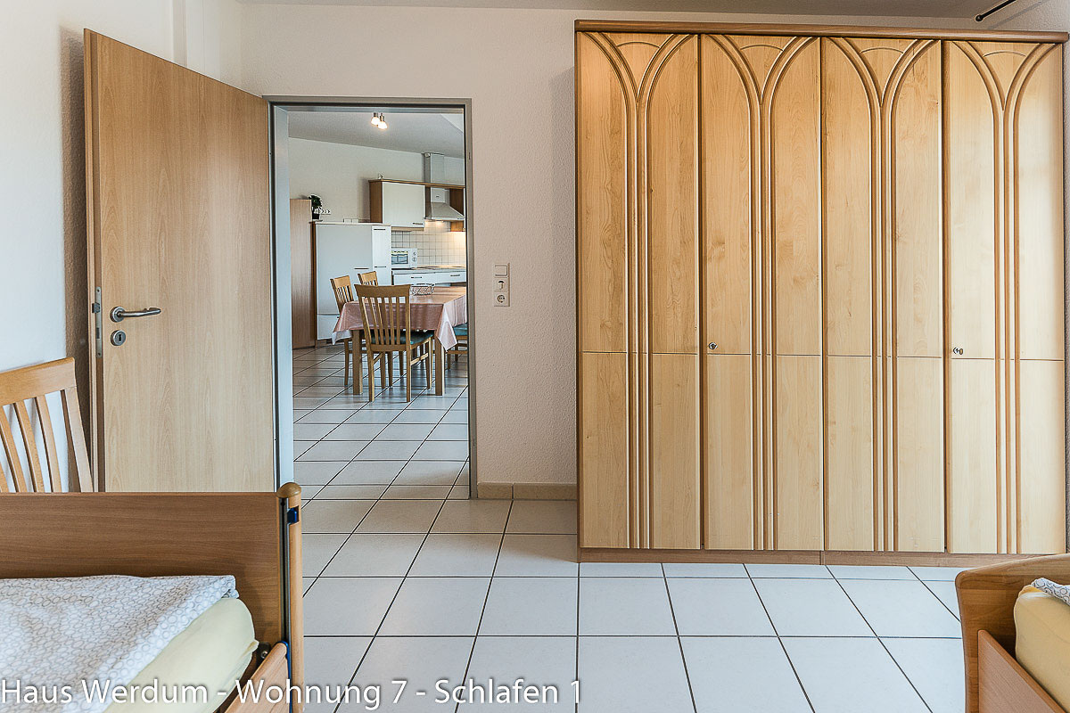 Schlafzimmer 1 mit großem Kleiderschrank, geöffneter Tür und Teilen der Pflegebetten. Reisen für Alle dokumentiert 350 × 150 cm Bewegungsfläche vor dem Schrank, einen schmalsten Durchgang von 150 cm sowie 93 cm Türbreite ohne Schwelle.