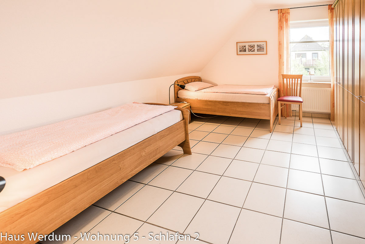 Helles, barrierefreies Schlafzimmer in Wohnung 5 im Haus Werdum mit zwei Einzelbetten aus Holz und schwellenlosem Fliesenboden für seniorengerechtes Reisen