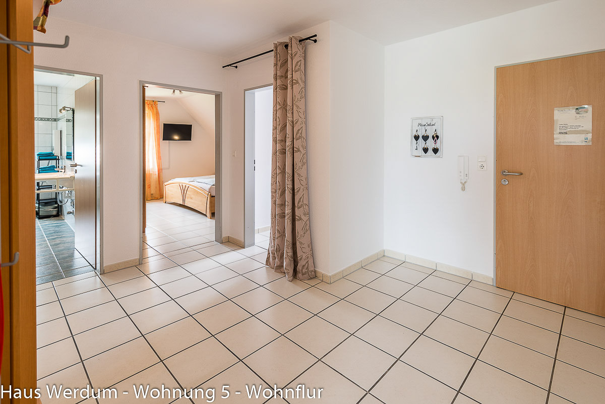 Zentraler Wohnflur in Wohnung 5 im Haus Werdum mit hellem Fliesenboden, Wohnungstür und barrierefreien Zugängen zu Badezimmer und Schlafzimmer