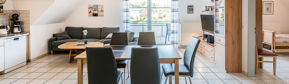 Offene Wohnküche der Wohnung 7 im Haus Werdum mit großem Esstisch, Küchenzeile, Wohnbereich, Balkonzugang und offenem Zugang zu Schlafzimmer 1. Laut „Reisen für Alle“ misst der Wohnraum etwa 6 × 6 m; der schmalste Durchgang beträgt 160 cm.